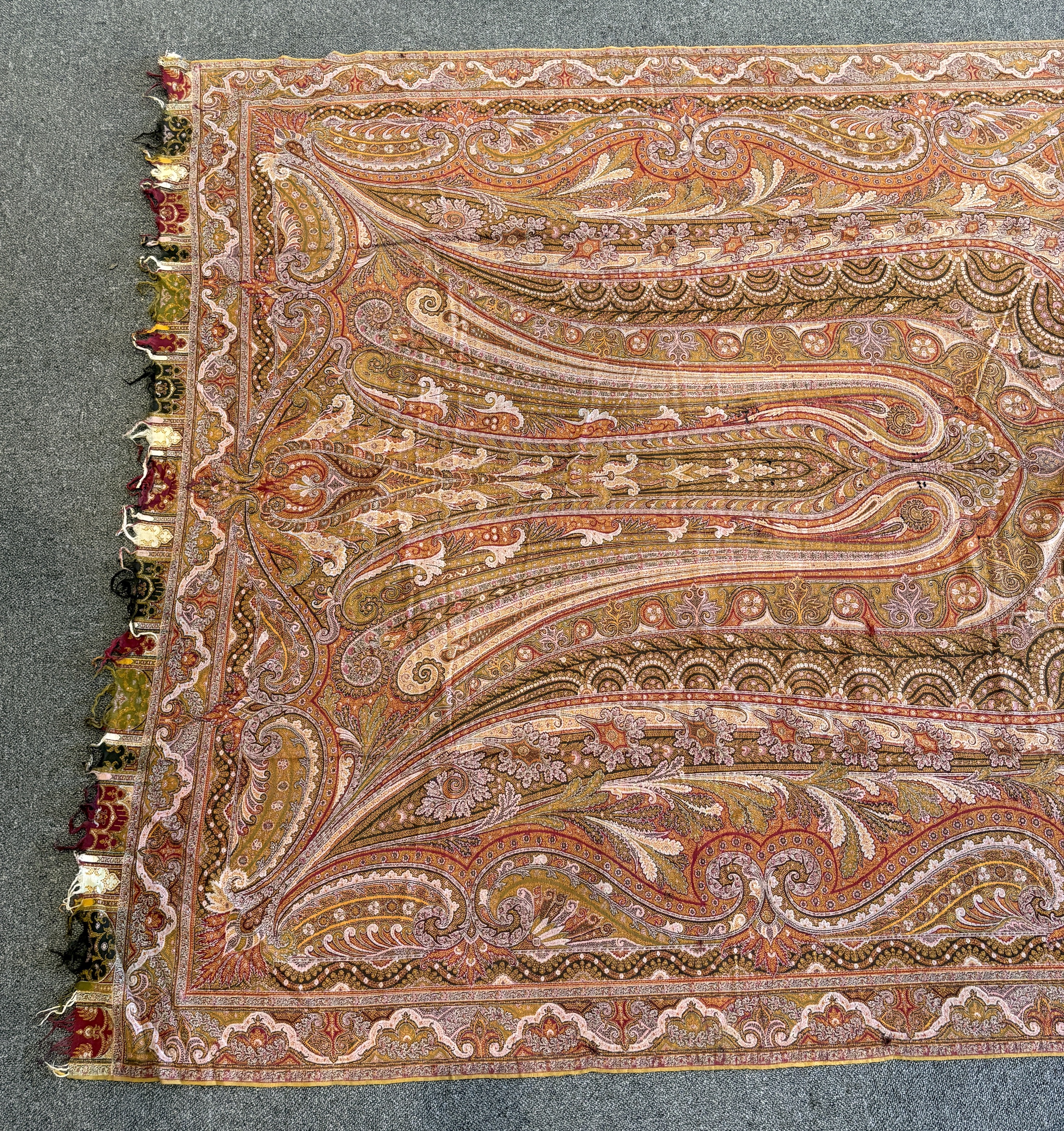 A 19th century woven Scottish Paisley wool shawl, bordered on four sides and fringed on two, woven with two ornate teardrop designs and a central cartouche, 334cm long x 160cm wide